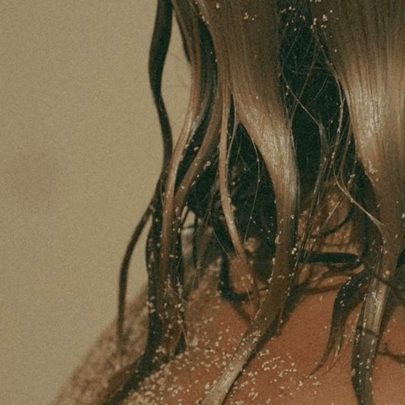 Close-up of a person with wet hair against a neutral background